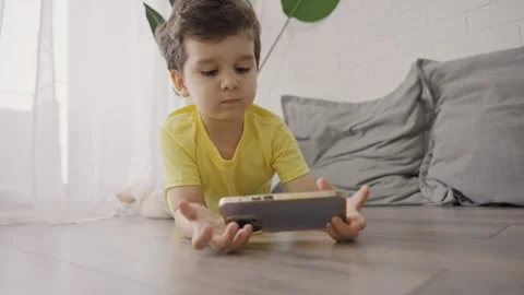 Small child taking smart phone on floor for play mobile games Stock Footage 245511312