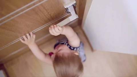A small child tries to open the door to the room, she can not do it and she Stock Footage 80296423