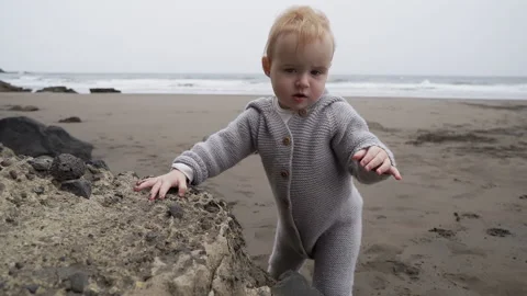 A small child walks along the sandy beach by the ocean. Stock Footage 146100421