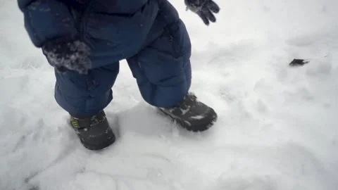 A small child walks through fresh snow. A boy in a down jacket steps on the snow Stock Footage 256526120
