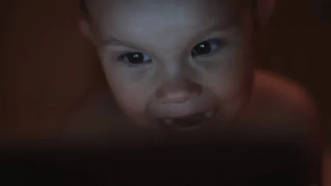 Small child is watching something on notebook and smiling. Stock Footage 77021180