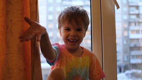 A small child at the window smiles. Face close-up. Sunlight through the window Video stock 104697113