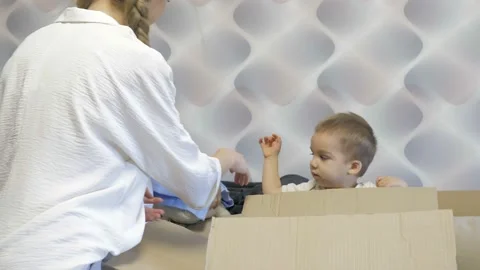 Small children cheerfully help their mother unpack boxes in a new apartment Stock Footage 165300801