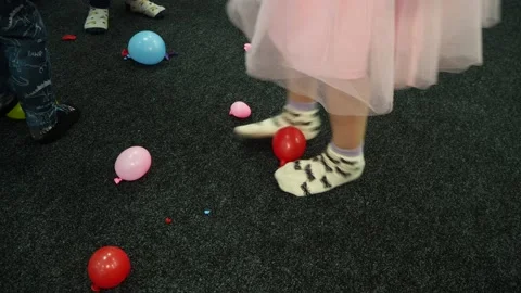 Small children jump trying to pop small inflatable balloons in the playroom. Video stock 168827271
