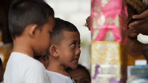 Small children receiving water blessing at Melukat Mebayuh Ceremonial in Bali Stock Footage