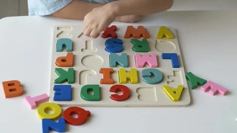 Small childs hand eagerly places vibrant letters into colorful alphabet puzzle Video stock 318294326