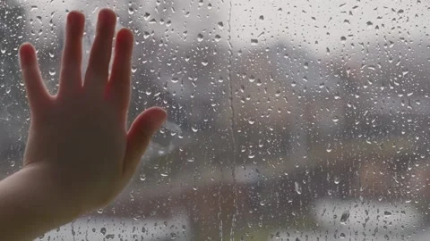 A small child's hand holding a window pane in raindrops  Stock Footage 150664342