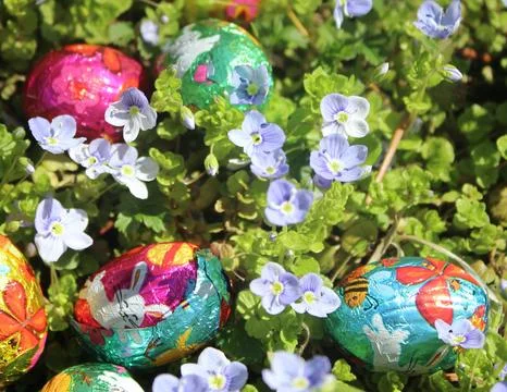 Small chocolate Easter eggs of multiple colors with decorative bunnies. Stock Photos