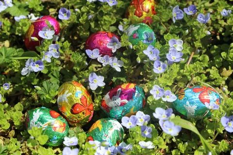Small chocolate Easter eggs of multiple colors with decorative bunnies. Stock Photos