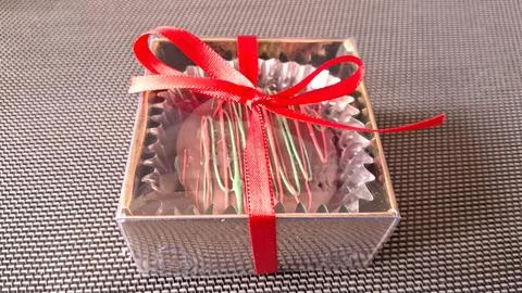 Small chocolate truffle gift box wrapped with a festive red ribbon Stock Photos