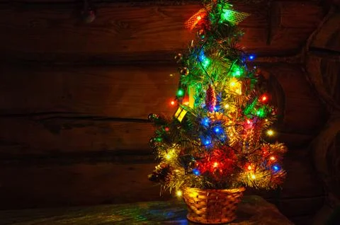 Small Christmas tree with multi colored lights at dark countryside room Stock Photos