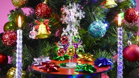 A small Christmas tree rotates between candles and a large Christmas tree Stock Footage 166840899