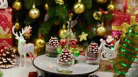 A small Christmas tree rotates on a stand, surrounded by pine cones Stock Footage 260887771