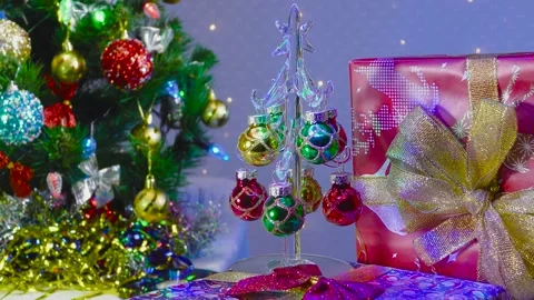 A small Christmas tree stands between a green Christmas tree and a gift Stock Footage 145111804