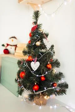 Small Christmas Tree Stands on Table with Red Toys. Vertical Card for Merry C Stock Photos