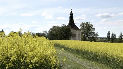 Small church, baroque chapel with belfry at field with oilseed rape 库存影片 123779233