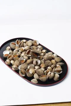 Small Clam Shells or called kerang darah in Asia On Black Plate Create Coas.. Stock Photos