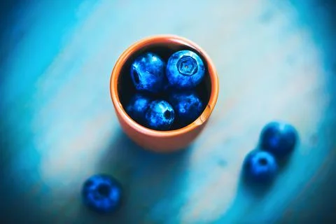 In a small clay cup with a chip on the edge are large ripe sweet blueberries, Stock Photos