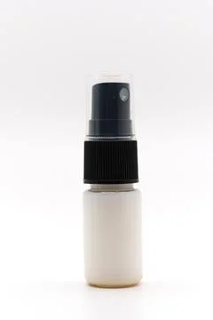 Small clear bottle with a black spray cap on a plain background Stock Photos
