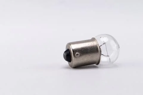 Small Clear Light Bulb with Silver Base on White Background, Close-Up Shot. Stock Photos
