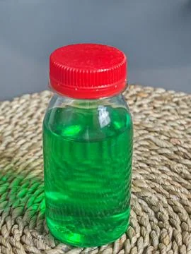 Small Clear Plastic Bottle with Red Cap Filled with Green Liquid Stock Photos