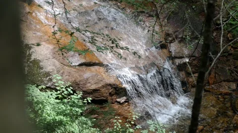 A small, clear waterfall runs off of a s... | Stock Video | Pond5