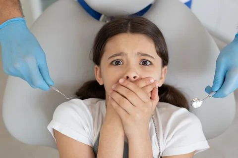Small client is afraid of dentist in dental office, overhead view Stock Photos