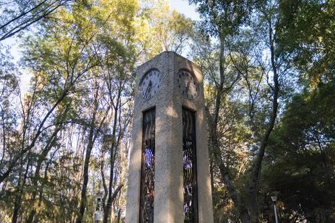 Small clock tower with trees and bright sunlight as background Stock Photos