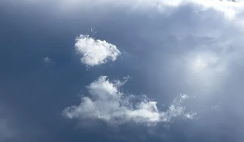 Small cloud formation floats in bright blue sky with sunlight. Minimal 스톡 사진