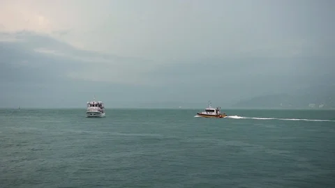 Small coast guard ship enters the open sea or ocean, circling pleasure boat Stock Footage 117437418