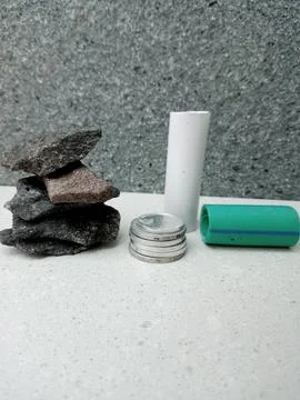 Small Coin Stack with Upright and Fallen Pipes Beside a Pile of Stones 스톡 사진