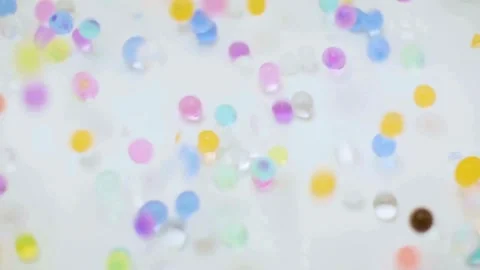 Small colorful translucent beads bouncing on a white background Stock Footage 333831411
