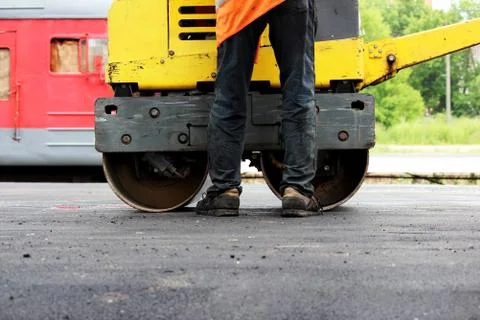 A small compactor covers with asphalt to platform at the railway station. Stock Photos