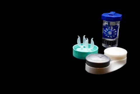 A small container of contact lens solution sits on a table next to a contact len Stock Photos