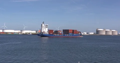 Small container ship sailing, oil and gas terminals in background Stock Footage 115715947