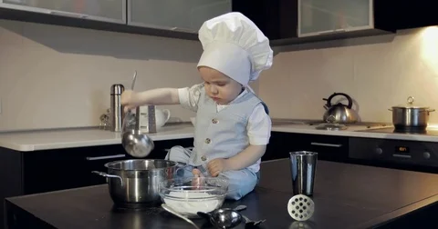 A small cook in a white culinary cap tries the flour in a metal saucepan. Stock Footage 85064558