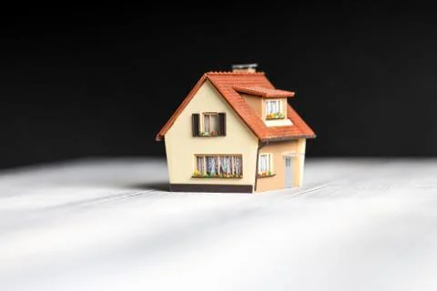 A small copy of the house is on the table on a black background. Stock Photos
