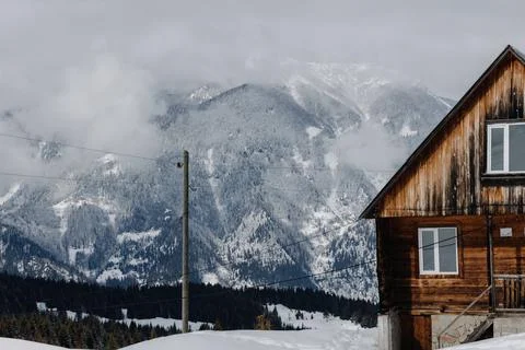 A small cozy hut located in front of the snow-capped mountains Stock Photos