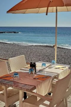 A small cozy table in the sun next to the calm sea. Stock Photos