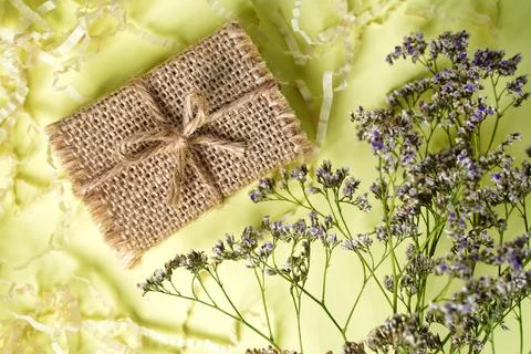 Small craft gift box rustic style on light yellow background with dry flowers Stock Photos