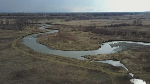 A small creek during winter next to trees and grass from a drone Stock Footage 167564157