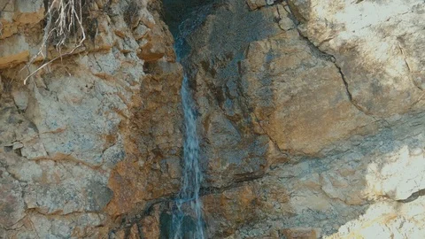 Small crevice with water flowing from run off at the entrance of a tiny Stock Footage 101777571