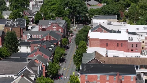 Small crowd of parade marchers walks narrow brick-lined street through downtown 库存影片 340968662