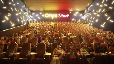 A small crowd seated on chairs and standing on the steps watch a film Stock Footage 137155520