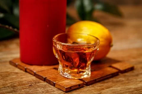 Small cup of brandy and lemon with candle Stock Photos