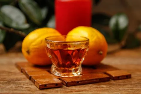 Small cup of brandy and lemon with candle Stock Photos