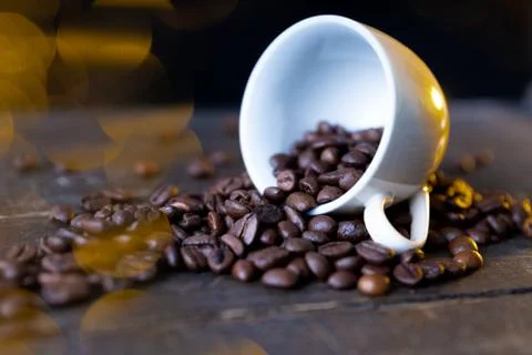 Small cup full of coffee beans on an old wooden table Stock Photos