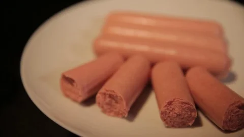 Small cut sausages lie on a white plate, the camera moves from left to right Stock Footage 75259296