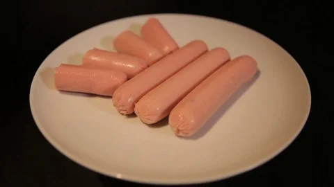 Small cut sausages lie on a white plate, the plate rotates from right to left Stock Footage 75259510
