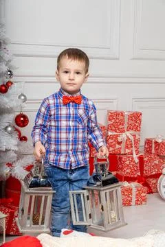Small cute boy casual dressed standing in white room among christmas decorati Fotos Stock